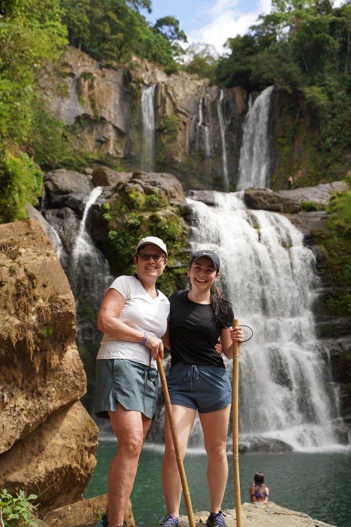 Ari and her mom standing together in front of a waterfall